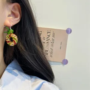 Detail view of handmade beaded Christmas tree earring worn on ear with crystal accents