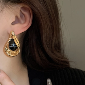 Vintage gold hollow teardrop earrings with black oval stones shown on a model