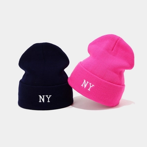 Close-up of NY embroidery on navy and pink knit beanies with fine ribbed texture