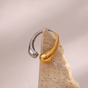 Detailed shot of teardrop-shaped open ring in gold and silver finish on stone