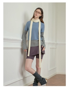 Detailed layered styling of a long cream knit scarf with a striped shirt and purple skirt