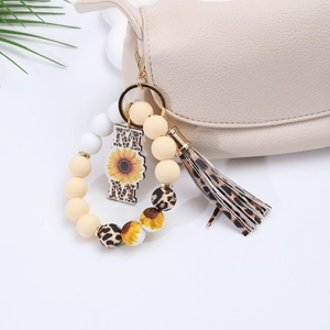 Detail of silicone bead keychain with MOM charm and leopard tassel on a beige bag