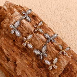 Detail of butterfly stud earrings with pearls and zircons on a textured wood background
