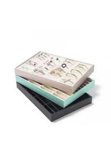 Detail of stacked multi-slot jewelry display trays in beige, green, and black velvet