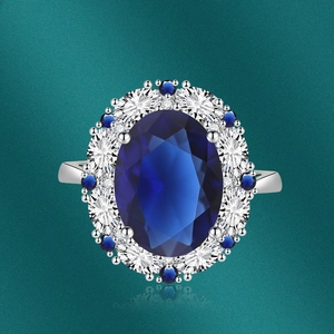 Macro detail of oval blue sapphire ring with white diamond halo and silver setting