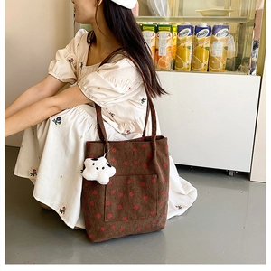 Brown corduroy bucket bag with red strawberry pattern and white star pendant on model