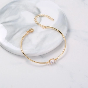 Detail view of gold metal tube bracelet with oval zircon and adjustable lobster clasp