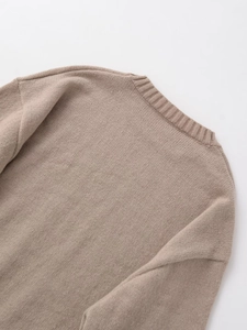 Close-up detail of the ribbed crewneck and soft knitted texture on beige knitwear