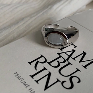 Close-up of silver adjustable ring featuring a large oval translucent gemstone on a book
