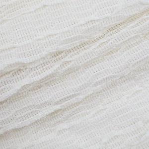 Détail rapproché d'un tissu blanc texturé avec vagues plissées et structure en maille
