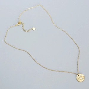 Close-up of golden O-chain necklace with a sparkling evil eye pendant and lobster clasp