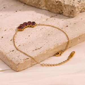 Detail of five pear-shaped red garnets set on a delicate 18K gold-plated chain bracelet