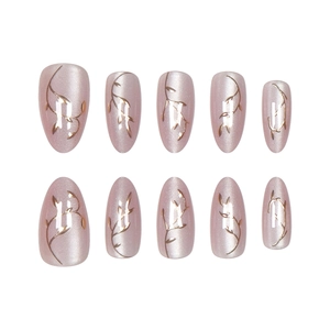 Macro detail of almond cat-eye fake nails with golden leaf embossing and metallic finish