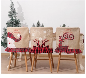 Three Christmas chair covers with Santa and reindeer patterns on a festive dining set