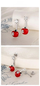 Detail of red apple stud earrings with silver leaf and crystal accents on cream background
