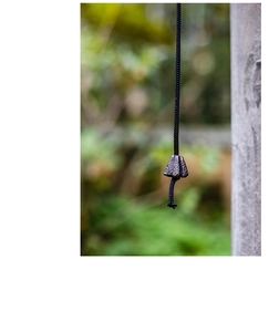 Detail of vintage cast iron garden bell with rustic texture hanging by a woven black cord