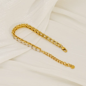 Detail eines Gold-Tennisarmbands mit klaren Zirkonia und Karabinerverschluss auf Stoff