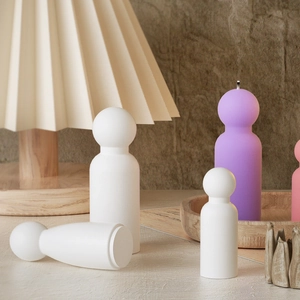 Minimalist geometric portrait candles in pastel colors displayed on a wooden tray