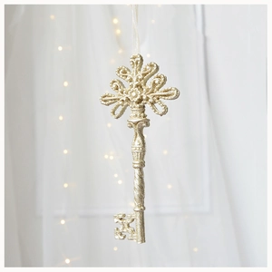 Detailed view of champagne gold glittery decorative key hanging on a soft tulle background