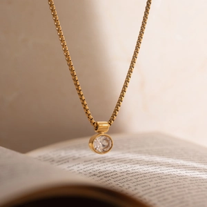 Detailed view of 18K gold plated box chain necklace with white egg-shaped zircon pendant