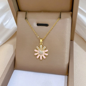 Detail of gold daisy pendant with pink enamel petals and diamonds in a jewelry gift box