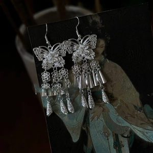 Close-up of silver hollow butterfly tassel earrings with intricate traditional pattern
