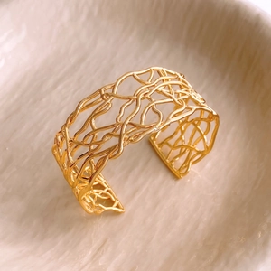 Close-up of 18K gold plated cutout cuff bracelet with organic bird nest design texture