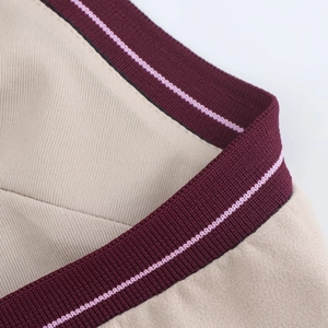 Dettaglio macro del tessuto a maglia beige con bordi a coste bordeaux e strisce rosa sottili
