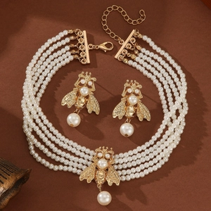 Elegant four-layer pearl necklace and earring set with golden bee charms on brown background