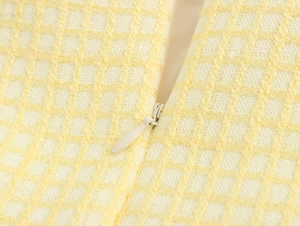 Dettaglio macro della cerniera invisibile su gonna in tweed a quadri gialli