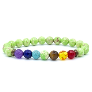 Detail view of colorful seven chakra beads and textured green stones on yoga energy bracelet