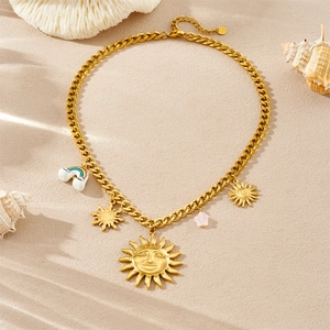 Gold-plated stainless steel Cuban link necklace with sun face and rainbow charms on beach sand