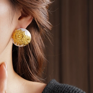 Close-up of vintage golden daisy earrings on model featuring large white round studs