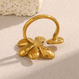 Detailed view of an 18K gold plated flower ring on a minimalist stone background