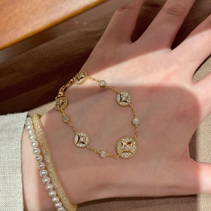 Close-up of 18K gold plated starburst charm bracelet layered with pearl cuff on wrist