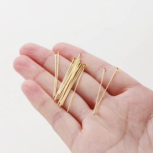 Detailed view of 18K gold plated T-pins held in hand for DIY jewelry making supplies