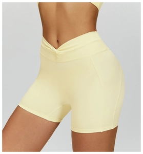 Dettaglio dei pantaloncini da yoga a vita alta con incrocio a V in tessuto giallo chiaro