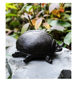 Macro view of vintage cast iron ladybug key box with rustic texture on stone base