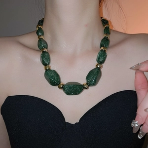 Detail of chunky acrylic necklace with dark green glitter beads and golden spacers