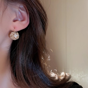 Gros plan de boucles d'oreilles fleur dorées avec nacre et cristaux sur mannequin