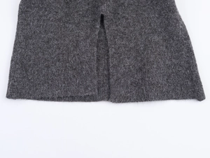 Detailed close-up of dark grey wool knit dress showing the precise side slit hem finish