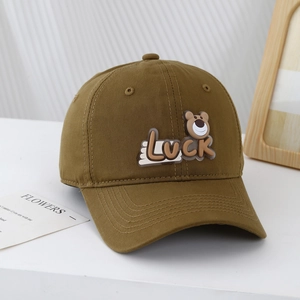 Close-up of brown cotton baseball cap featuring luck bear patch on a minimalist desk