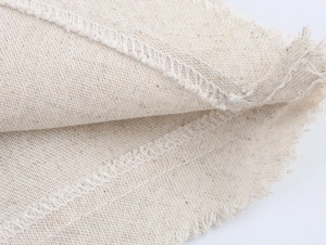 Detail of beige linen fabric texture with raw frayed edges and white overlock stitching