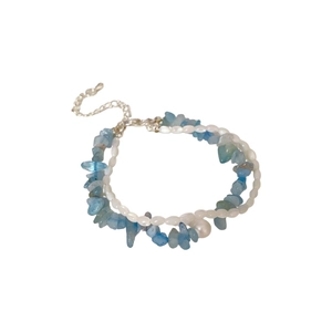 Double-layered bracelet with irregular blue stones and white baroque pearls on white background