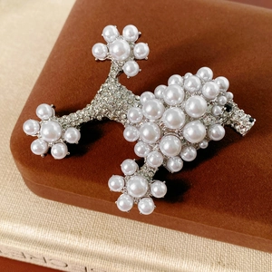 Detailed macro view of vintage poodle brooch with pearls and rhinestones on velvet