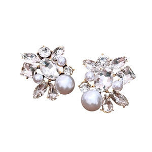 Elegant gold earrings with sparkling crystals and drop pearls on a white background