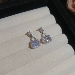Detailed close-up of square zircon drop earrings with silver plating on jewelry box padding