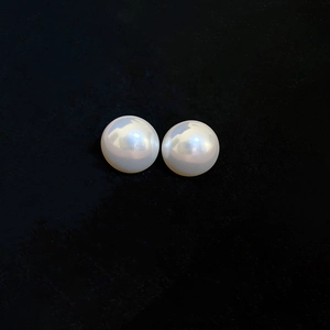 Detail view of high-lustre white round pearls on black velvet for silver stud earrings