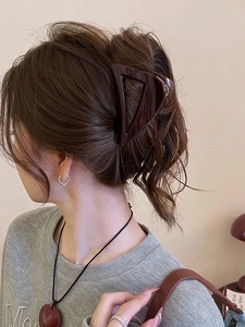 Macro detail of a dark brown triangle hair claw clip in a stylish high ponytail setting