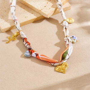 Detailed flat lay of printed silk scarf necklace with colorful charms and heart pendant